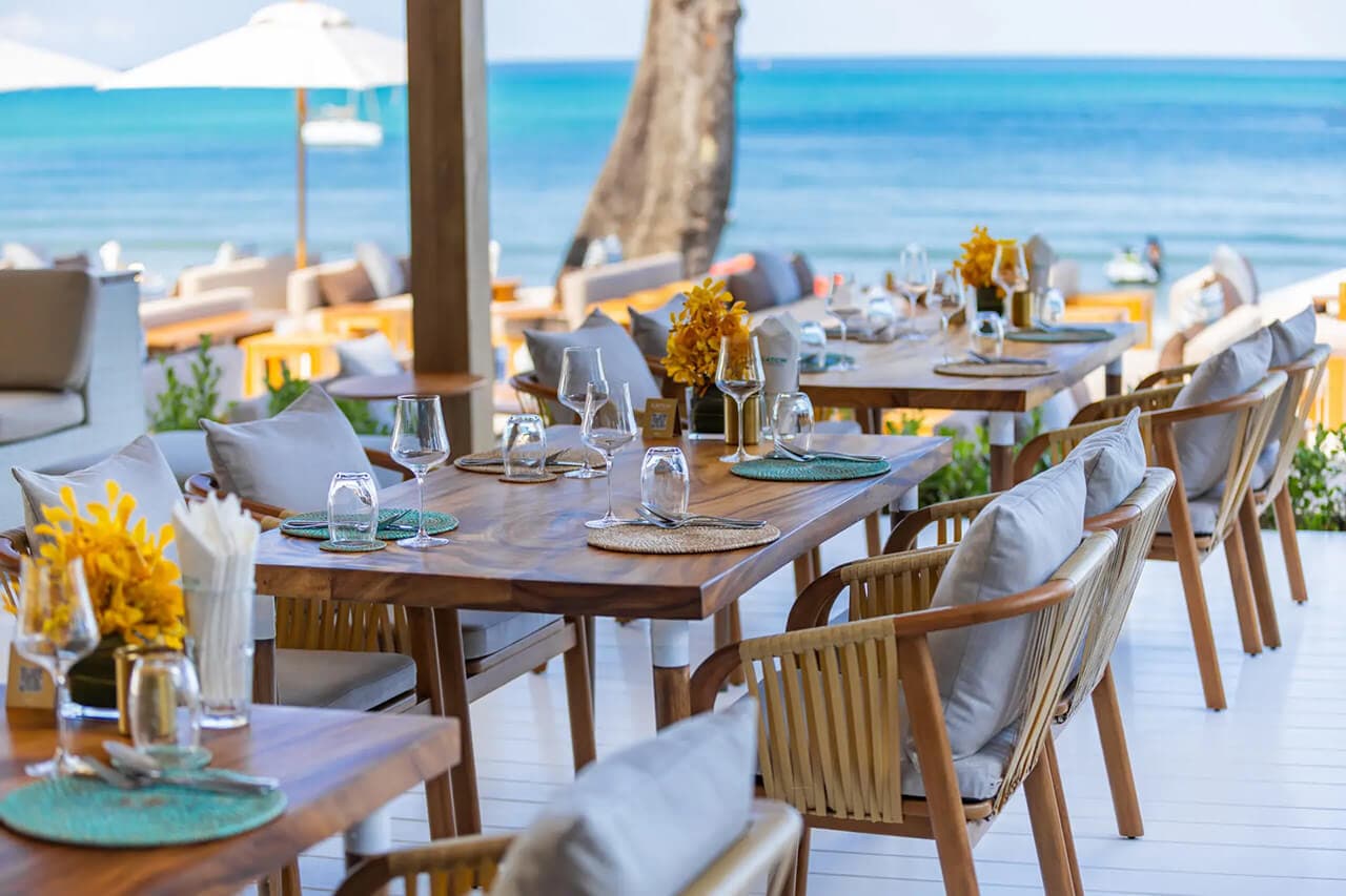Beachfront dining table set for sunset at a Bang Tao beach club in Phuket