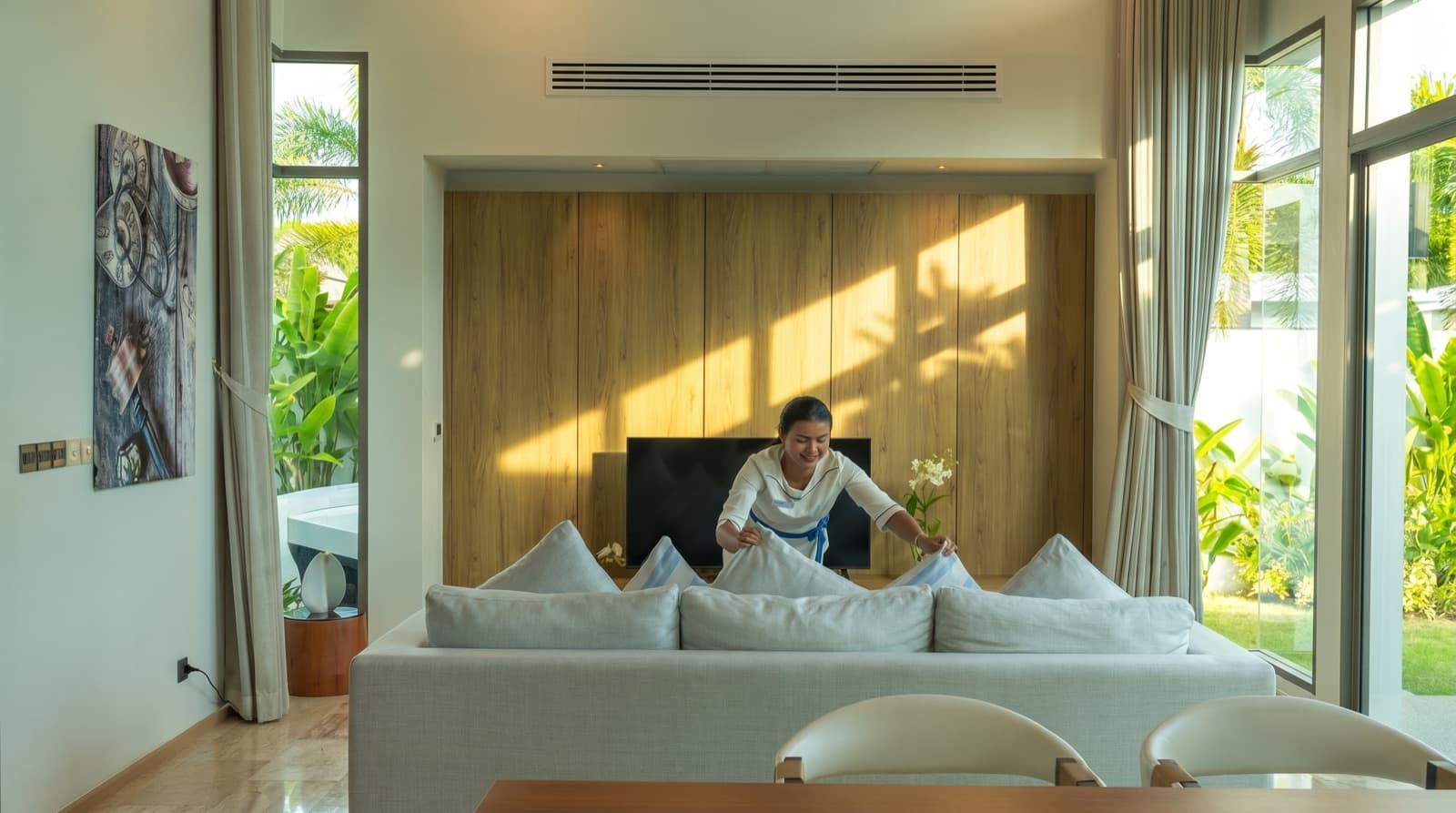 Housekeeper arranging cushions in a Phuket villa living room