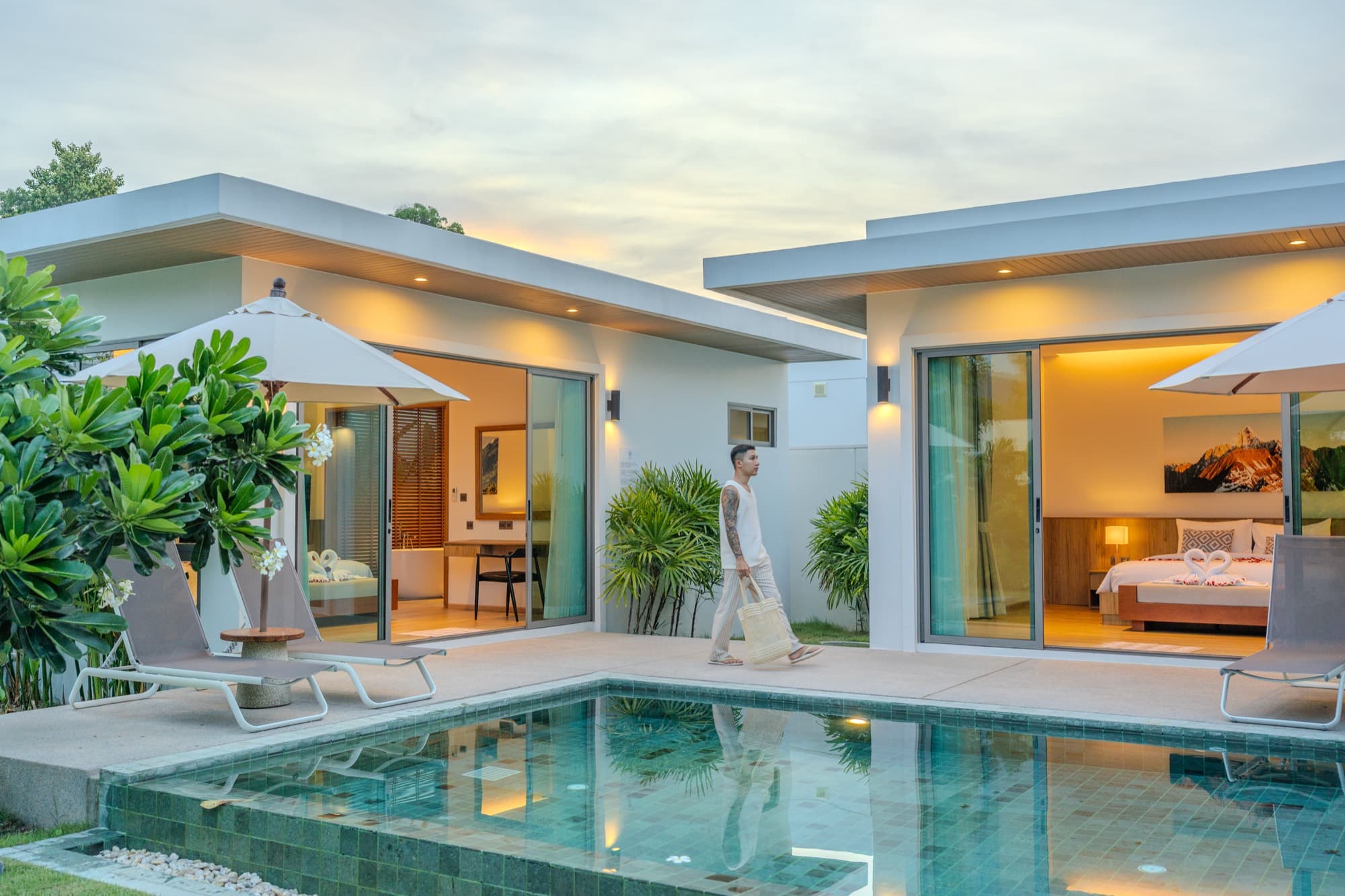 A guest walking past the pool of a private villa at dusk in Phuket